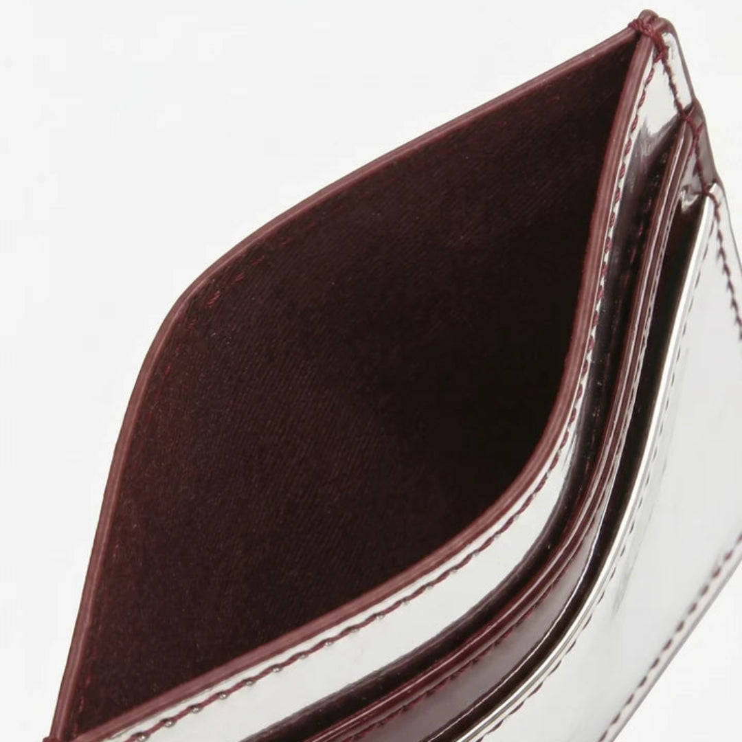 Close-up of an open cardholder wallet showing a maroon interior and glossy burgundy-brown edges on a white background.