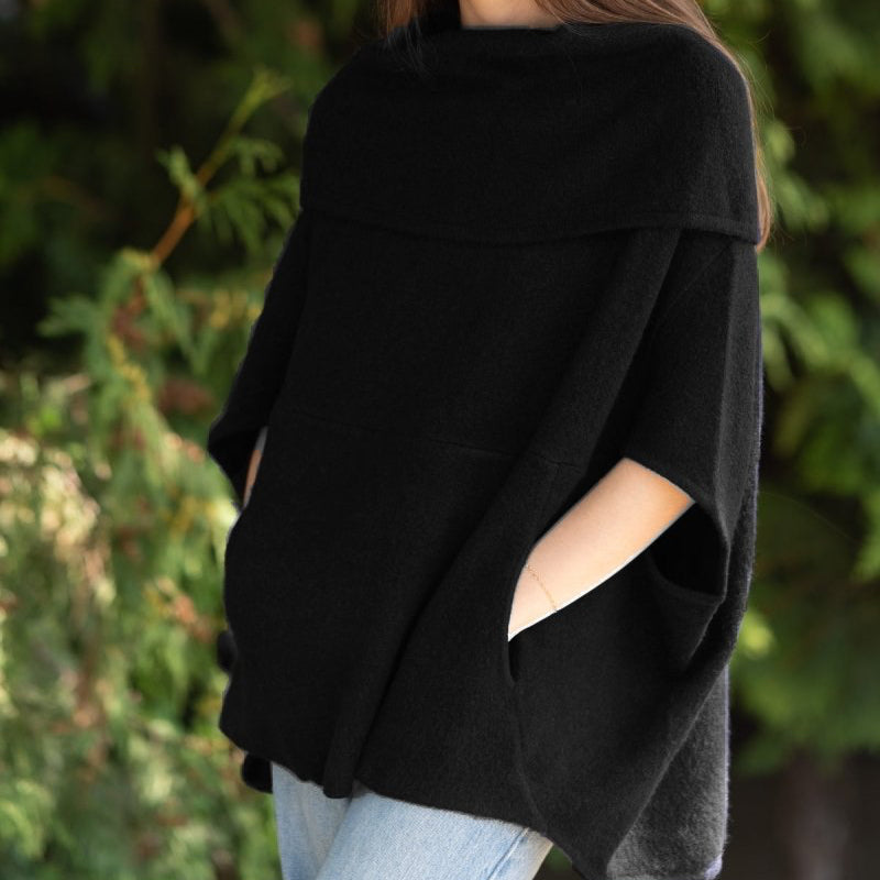 Woman wearing a black poncho with a blurred green background